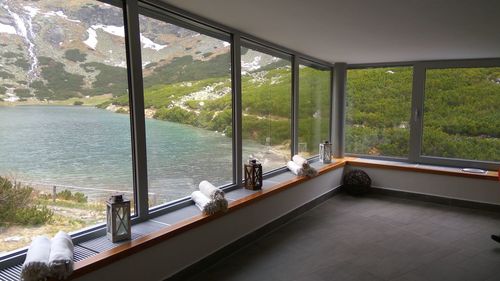 Railing by sea against sky seen through window
