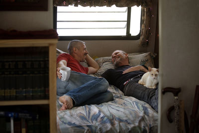 Happy gay couple sleeping on bed in camper van