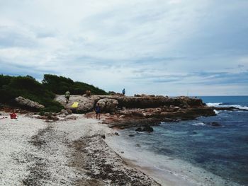 Birds perching on beach against sky