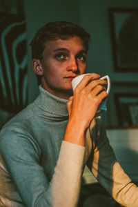 Thoughtful young man drinking coffee while sitting at home