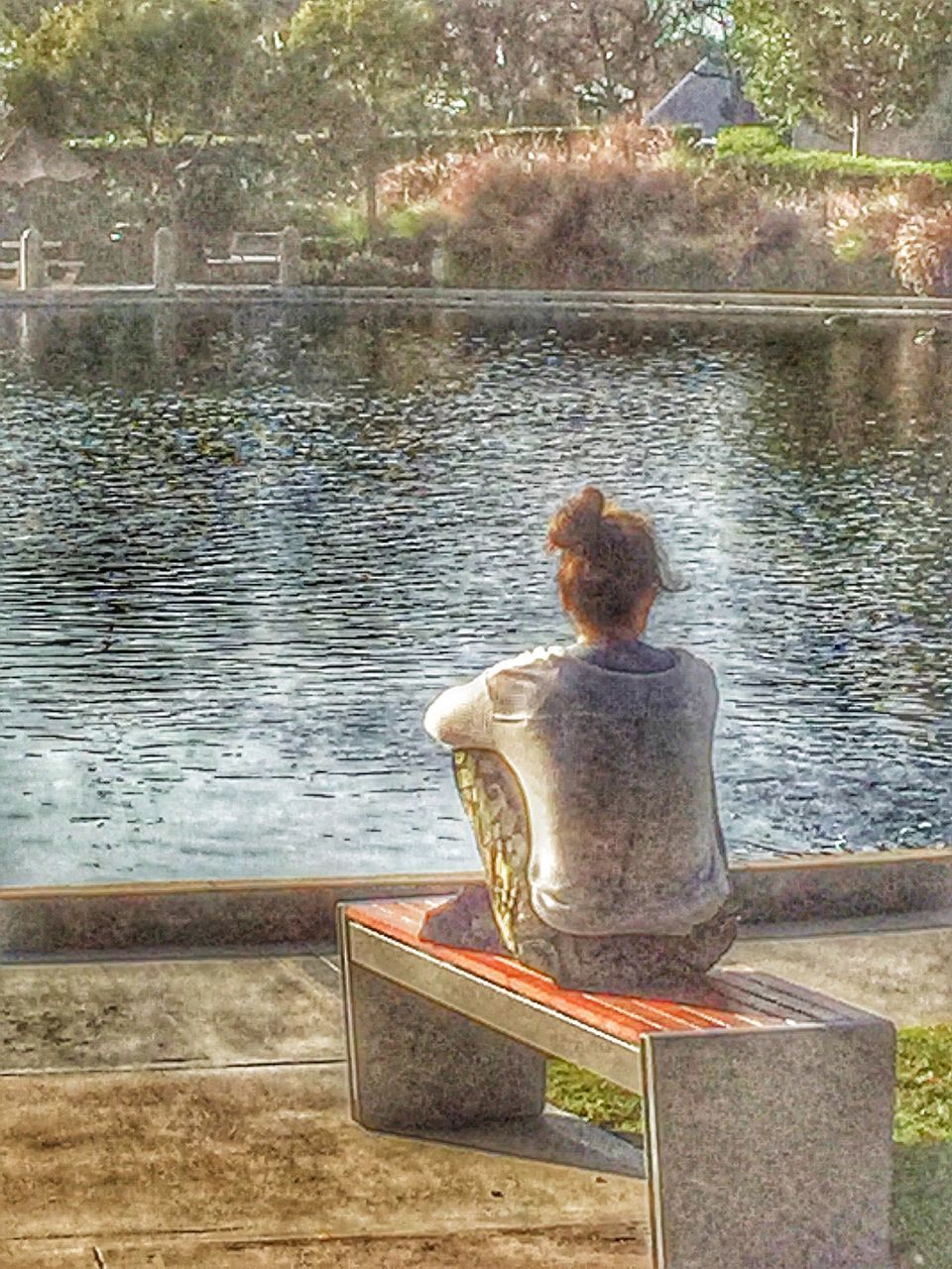 REAR VIEW OF WOMAN SITTING ON LAKE