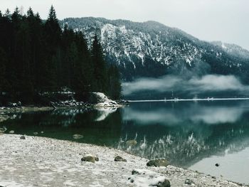 Scenic view of lake by mountains during winter