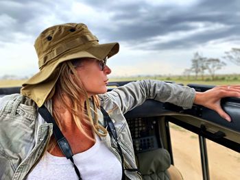 Woman wearing hat sitting in jeep against sky