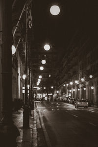 Illuminated street amidst buildings in city at night