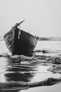 Boat moored on beach against clear sky
