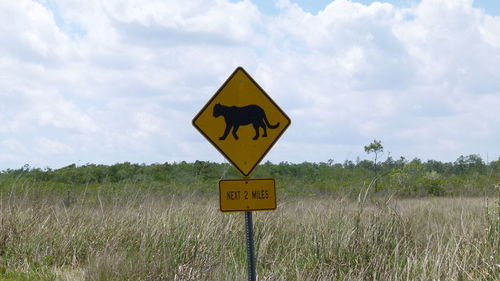 Information sign on field against sky