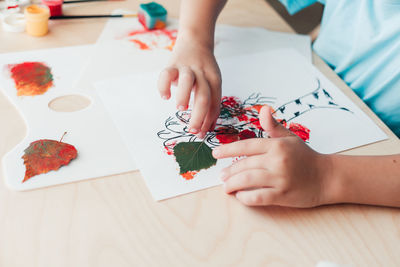 High angle view of baby hand holding paper at table