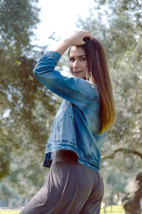 Portrait of beautiful young woman standing against trees