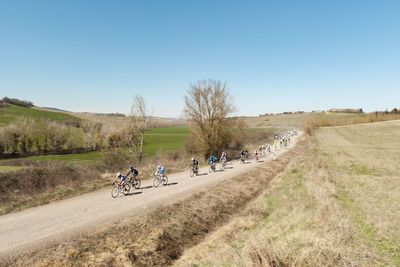 High angle view of bikers riding bicycles on dirt road against sky