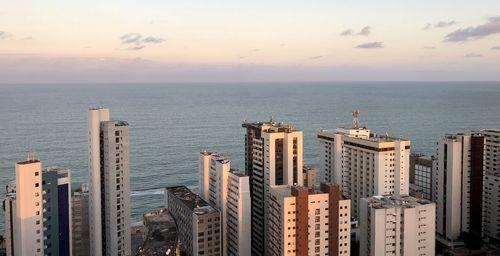 High angle view of buildings by sea against sky during sunset