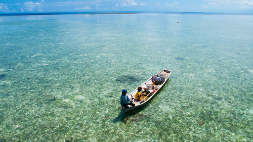 People sailing in boat at sea against sky