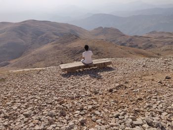 Rear view of man looking at mountains while sitting on seat