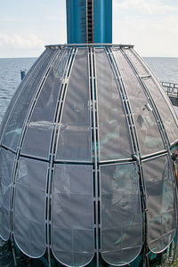 Close-up of metallic structure by sea against sky