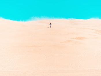 Distant view of woman standing on desert against clear sky