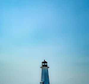 Low angle view of lighthouse by building against clear blue sky