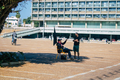 People playing on street against buildings in city