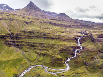 Scenic view of stream amidst mountains against sky