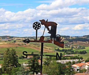 Close-up of rusty sign on field against sky