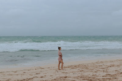 Rear view of man standing on beach against sky