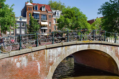 Arch bridge over canal amidst buildings against sky