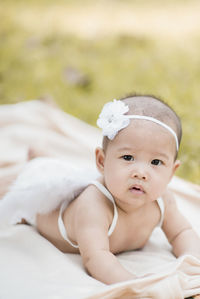 Portrait of cute baby girl wearing costume wing while lying on blanket