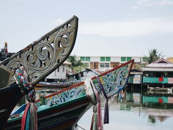 Fishing boat moored by river against sky