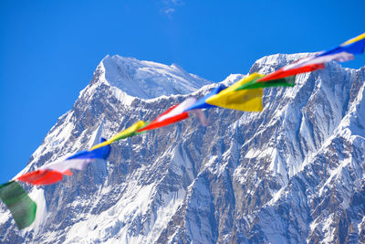 Colorful prayer flags hanging against mountains during sunny day