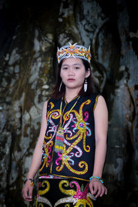 Portrait of young woman standing against trees