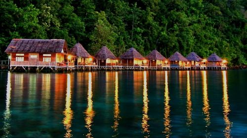 Houses by lake and buildings against trees