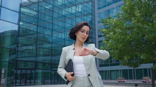 Calm businesswoman looking time on hand watch while going to the work after break