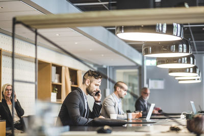 Male and female business people working at table in office