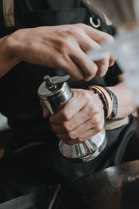 Midsection of barista holding coffee grinder