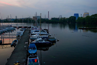 Boats moored at harbor during sunset