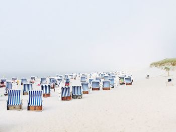 Deck chairs on beach against clear sky