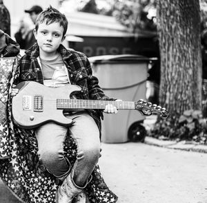 Portrait of cute boy with guitar sitting outdoors