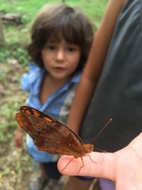 Cute boy looking at butterfly on finger