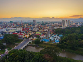 High angle view of river amidst buildings against sky during sunset