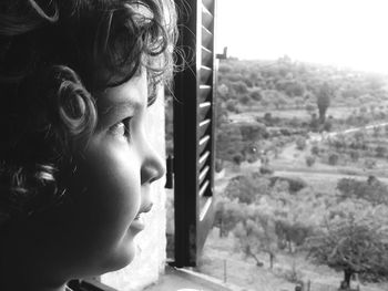 Close-up of boy looking through window