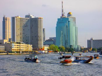 Boats in sea against buildings in city