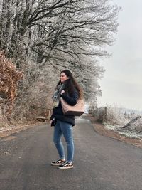 Full length portrait of woman standing on road in winter