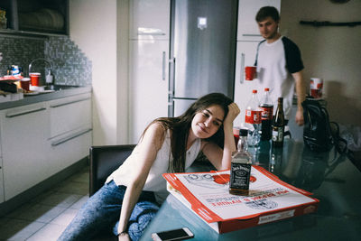 Young woman looking down while sitting on table at home