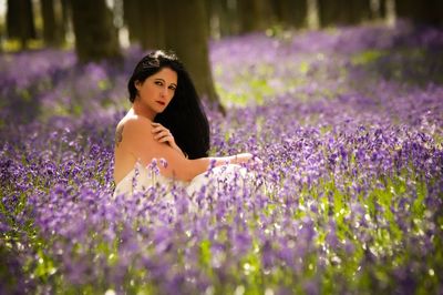 Portrait of woman with purple flowers on field