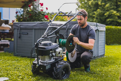 Man repairing lawn mower at yard