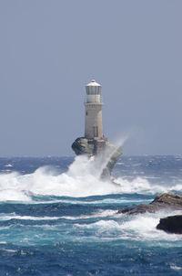 Lighthouse by sea against clear sky