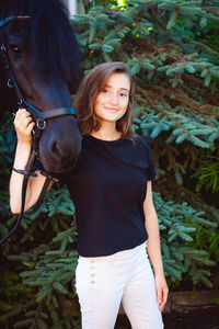 Woman with horse standing against plants