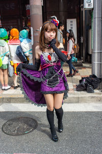 Full length of girl holding umbrella on street in city