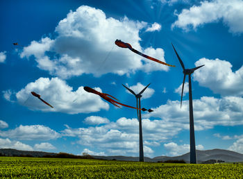 Flying kites and windmill against sky