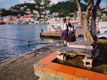 Rear view of people standing on riverbank in city