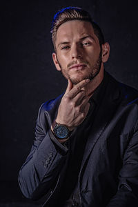 Portrait of young man against black background