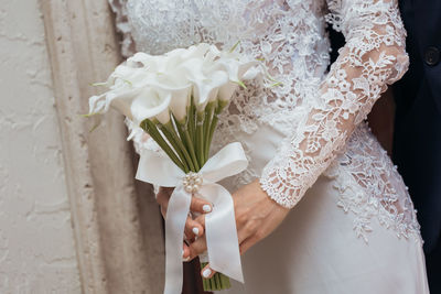 Midsection of bride holding bouquet